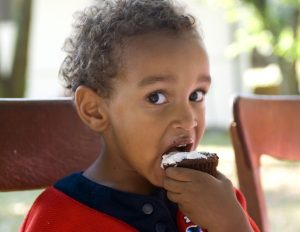 A young african american boy eating birthday cake.