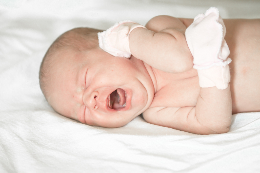 newborn baby with mittens crying