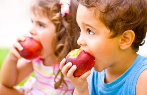 two happy children eating apples
