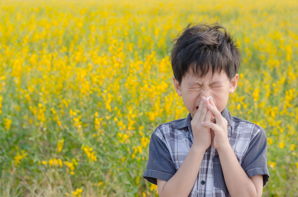 child blowing his nose next to field