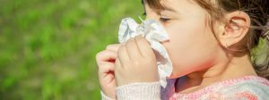 small girl blowing her nose outdoors